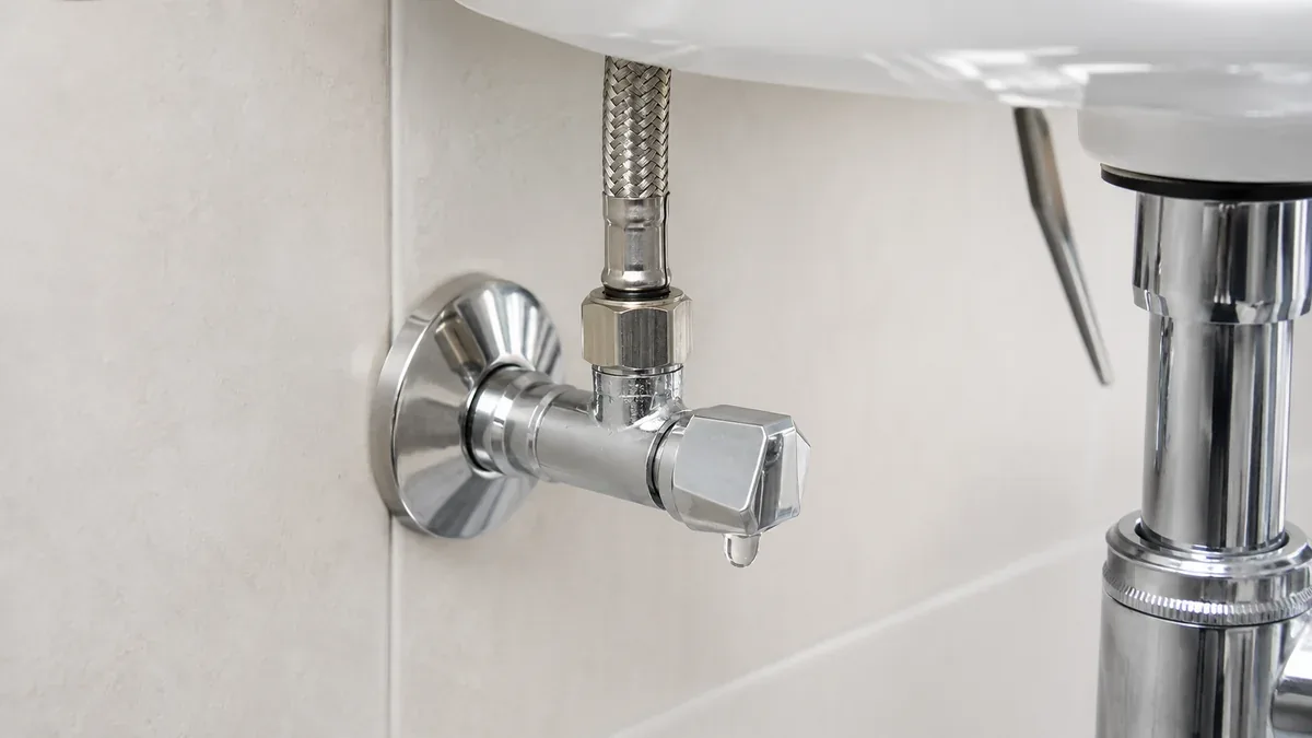 Tropfendes Eckventil unter einem Waschbecken mit sichtbarer Feuchtigkeit am Flexschlauchanschluss